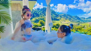 Two people in a hot tub with a scenic landscape view in the background. - Cherpue Chiangmai (Mae Taeng)