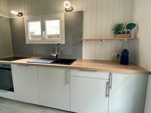 Moderni keittiö, jossa on musta allas, valkoiset kaapit ja puinen työtaso.