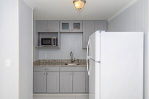 A compact kitchen with a built-in microwave, a sink, and a white refrigerator. - A Leave of Absence - 5BR Canalfront Home with Covered Porches and Boat Dock (Topsail Beach)