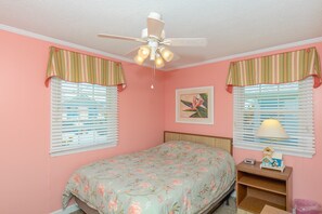 A bedroom with a bed, a ceiling fan, a nightstand, and a window with blinds.