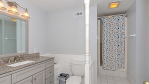 A bathroom with a sink, mirror, vanity, toilet, and shower curtain.