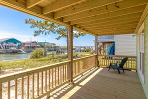 A wooden deck with a railing, a chair, and a view of a marina with boats and buildings.