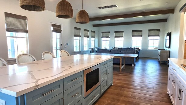 A spacious kitchen with a large island, wooden flooring, and pendant lighting. - Ultimate Beach Escape -4BR Luxury with EV Charging (Galveston)