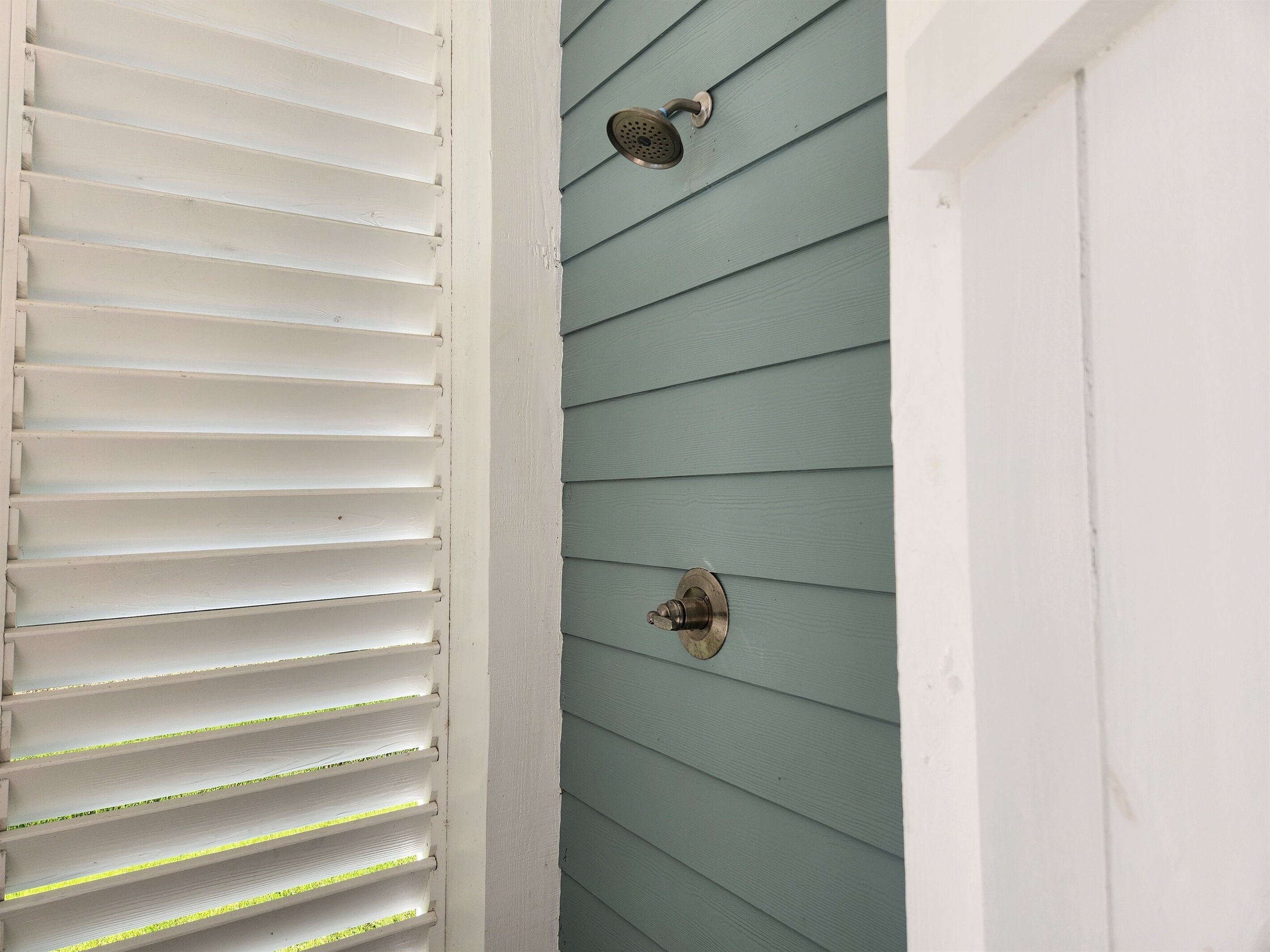 A corner of a room with white blinds and a light blue wall.