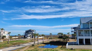 A coastal residential area with houses, a small pond, and a clear sky. - Ultimate Beach Escape -4BR Luxury with EV Charging (Galveston)