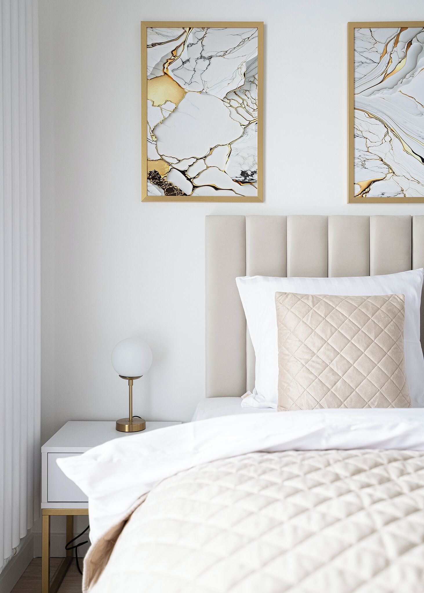 A bedroom with a bed, nightstand, lamp, and two framed abstract art pieces on the wall.