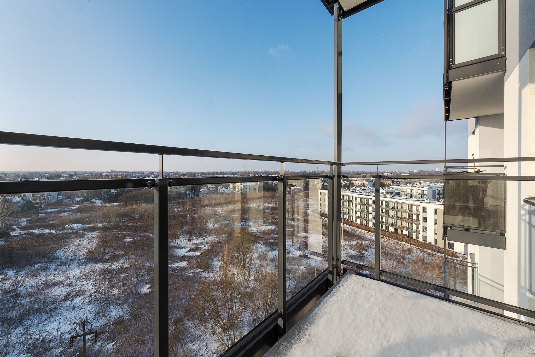 A balcony with a view of a snow-covered landscape and buildings.