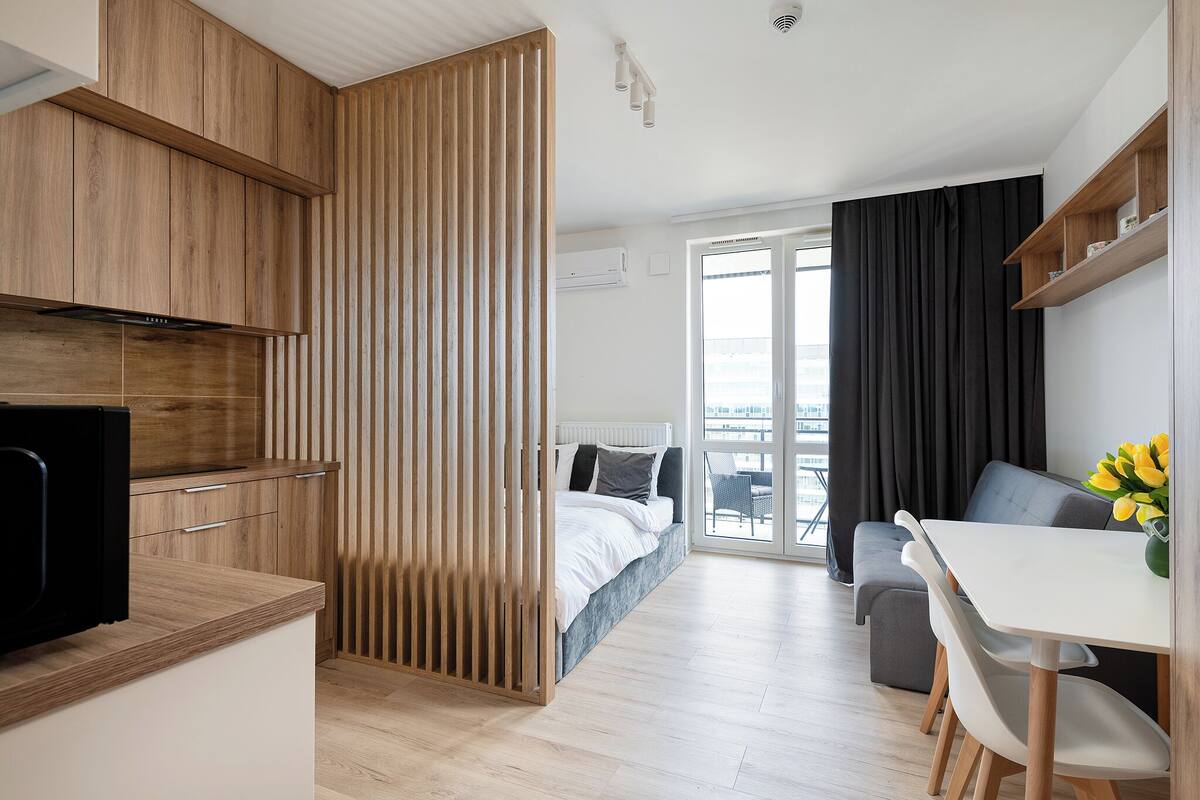 A modern apartment with a kitchen, dining area, and a balcony with a view.