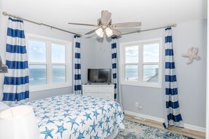 A bedroom with a bed, a ceiling fan, a TV, and windows with curtains. - Sea Glass - Fantastic Views from this 3 BR Oceanfront Home! (Surf City)