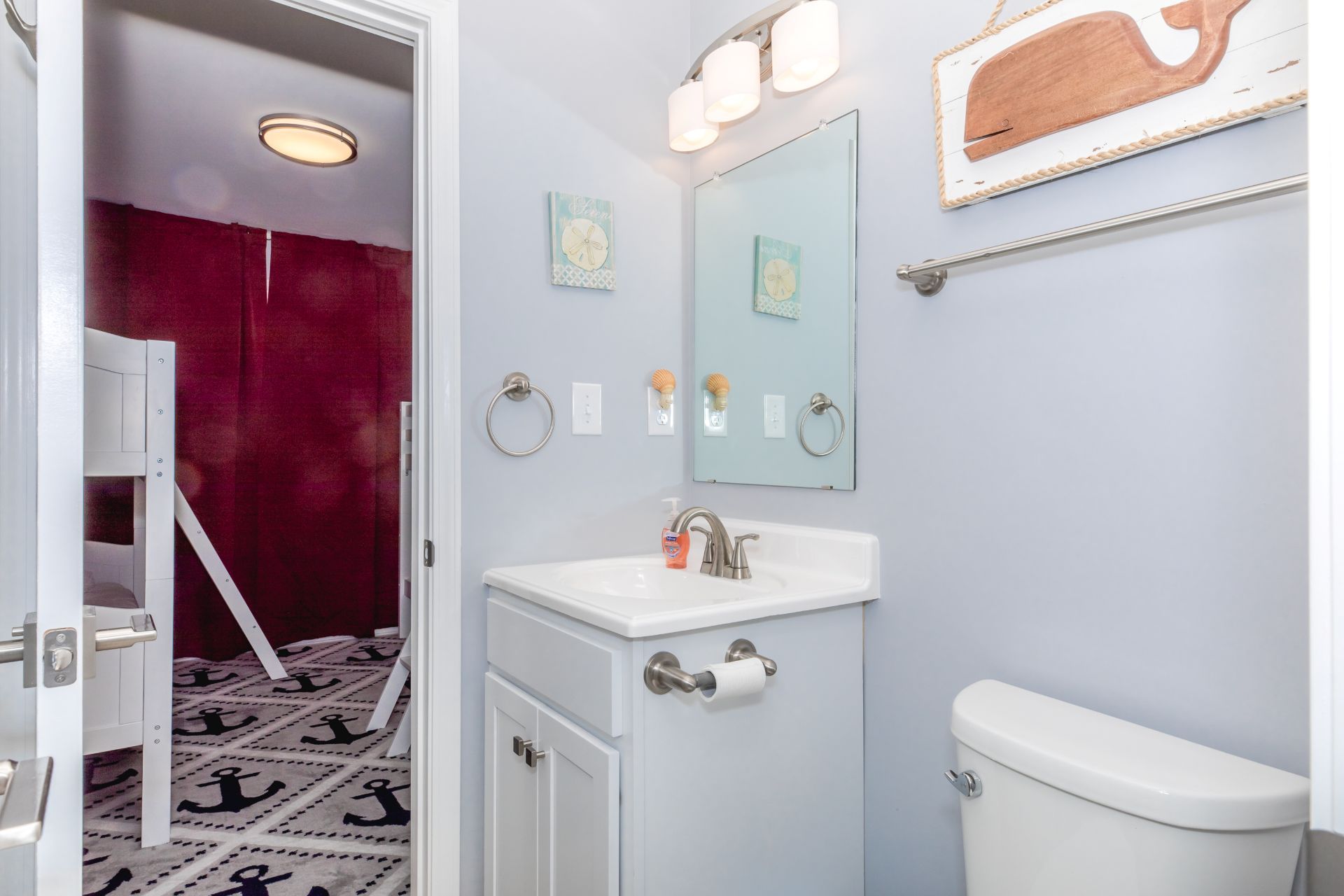 A bathroom with a white sink, a toilet, a mirror, and a vanity with a towel ring.