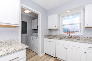 A kitchen with white cabinets, a granite countertop, a built-in dishwasher, and a window with a view of the beach. - Sea Glass - Fantastic Views from this 3 BR Oceanfront Home! (Surf City)