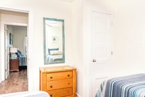 A bedroom with a bed, a dresser, a mirror, and a door. - Beach Barn - Nice 5BR Oceanfront Home in Heart of Surf City (Surf City)