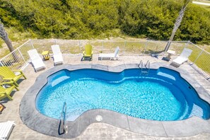 Une piscine à bord incurvé, entourée d’une clôture et dotée d’une échelle.