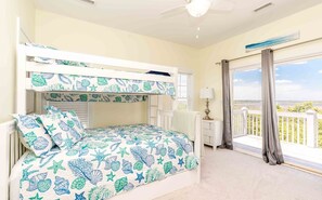 A room with a bunk bed, a small desk, a lamp, and a balcony with a view. - Wells Beach Paradise - Awesome 5BR Home - Pool, Hot Tub, Great Ocean Views! (North Topsail Beach)