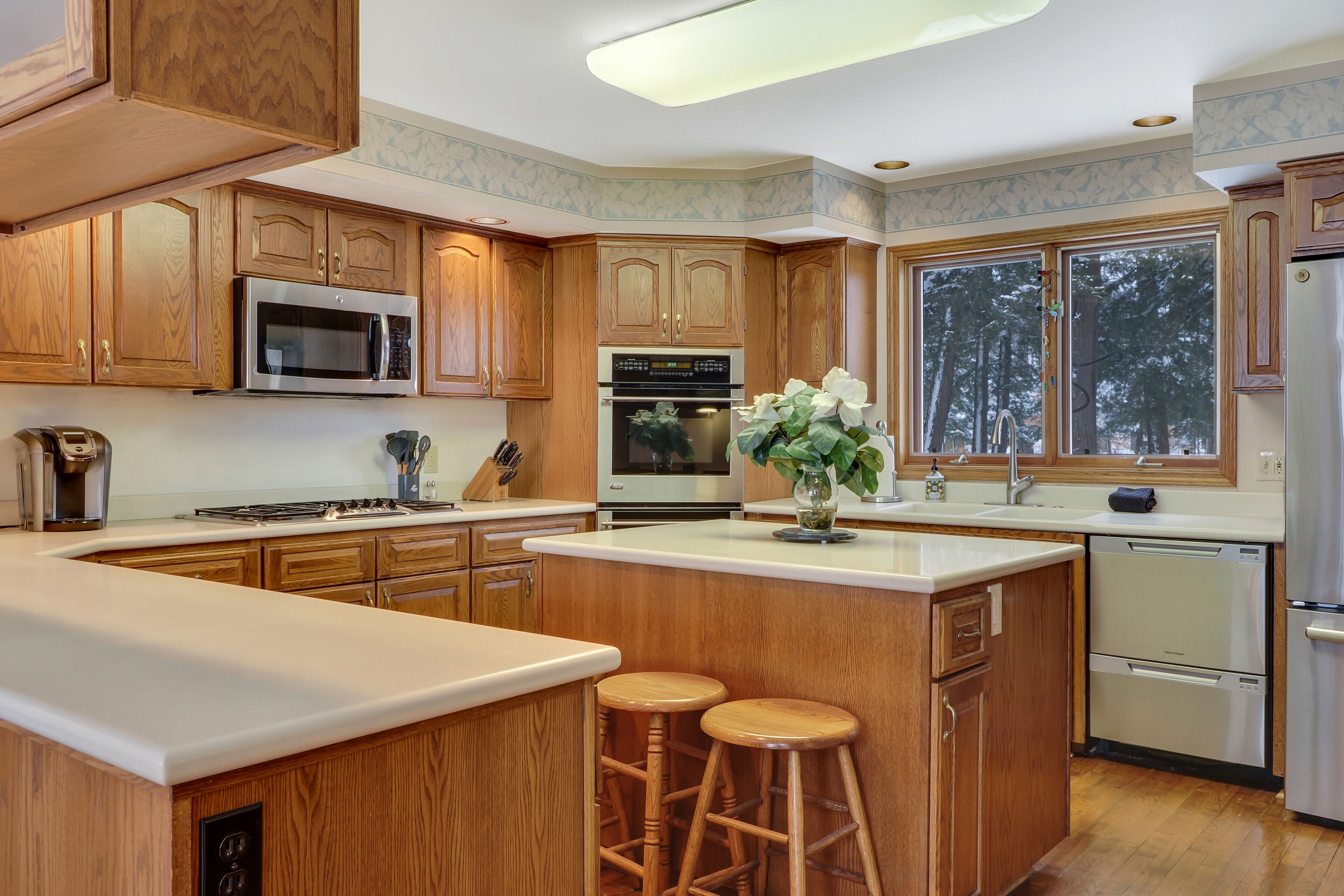A spacious kitchen with wooden cabinets, stainless steel appliances, and a large island with stools.