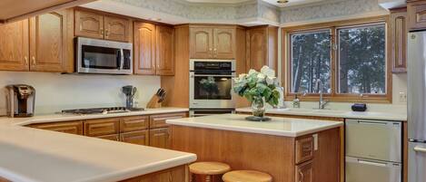 A spacious kitchen with wooden cabinets, stainless steel appliances, and a large island with stools.