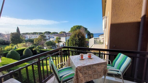 Un balcon avec une table et des chaises, donnant sur un quartier résidentiel avec des maisons et offrant une vue sur la mer.