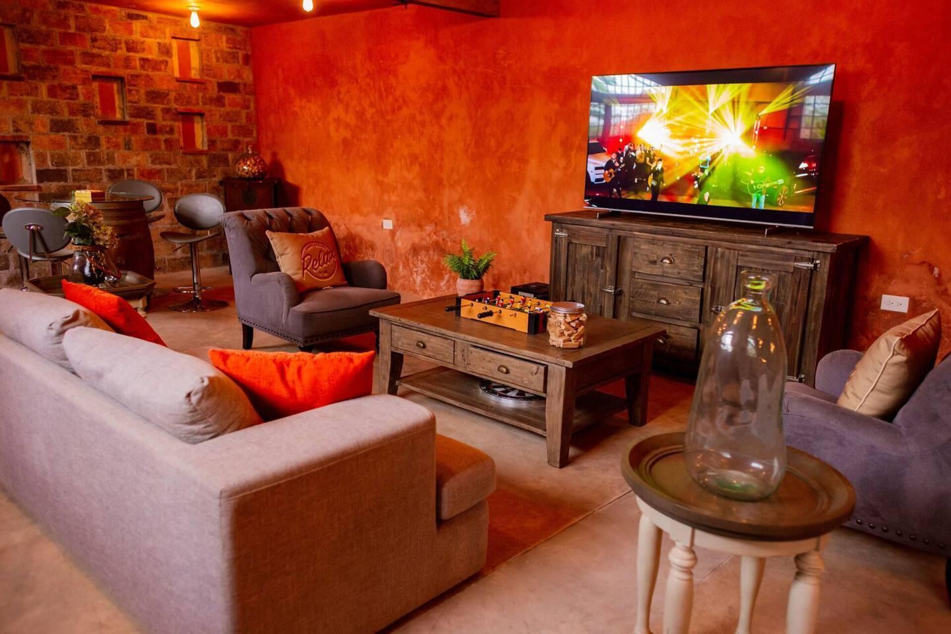 A cozy living room with a sofa, armchairs, a coffee table, and a television displaying a concert.