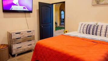 A bedroom with a bed, a television, a wooden chest, and a door leading to another room.