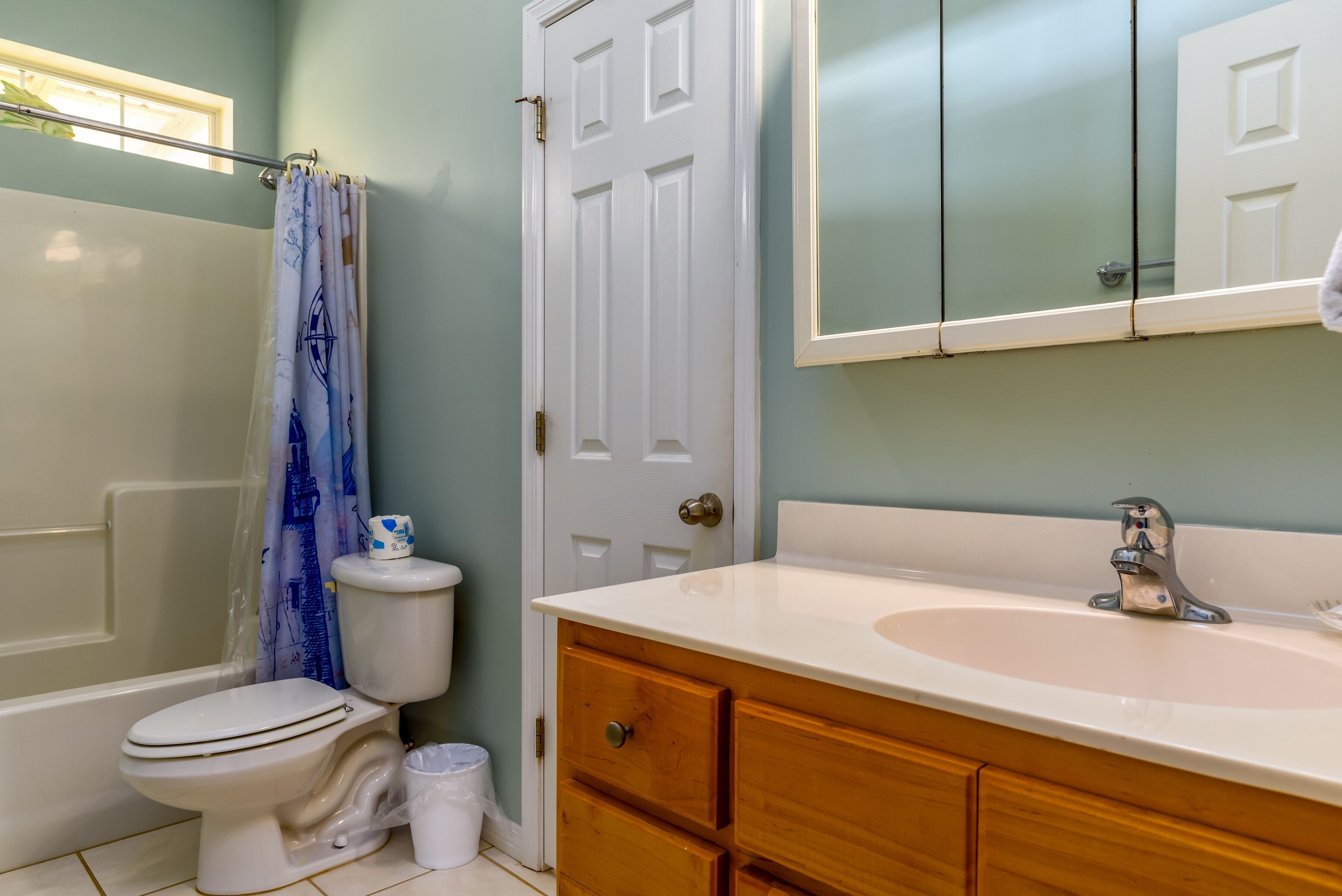 A bathroom with a toilet, a sink, wooden cabinets, and a mirror.