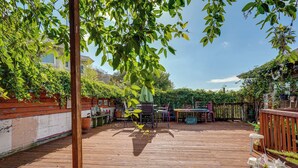A wooden deck with a table and chairs, surrounded by greenery and a wooden fence. - Downtown Oakland Studio, 6 Mi to Toll Plaza Beach! (Oakland)