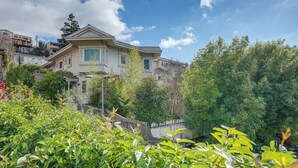 A residential building with a prominent entrance, surrounded by lush greenery and a clear blue sky. - Downtown Oakland Studio, 6 Mi to Toll Plaza Beach! (Oakland)