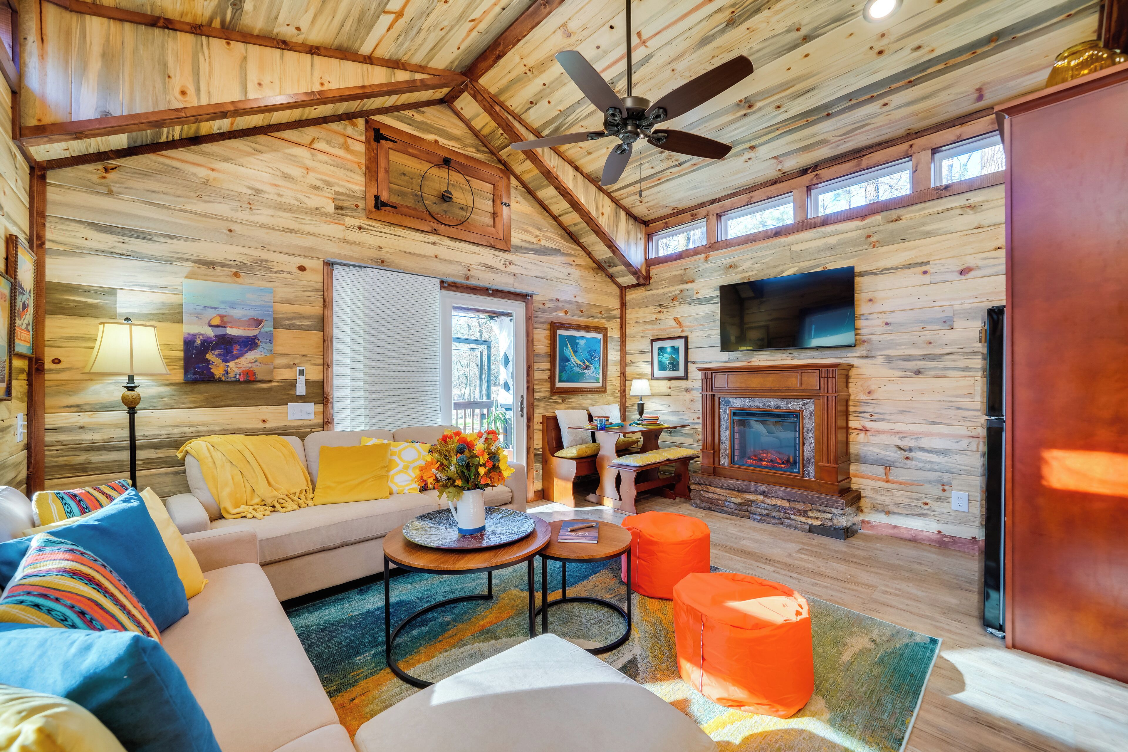 L’intérieur chaleureux d’un chalet avec un plafond en bois, une cheminée, un canapé, une table à manger et un téléviseur.