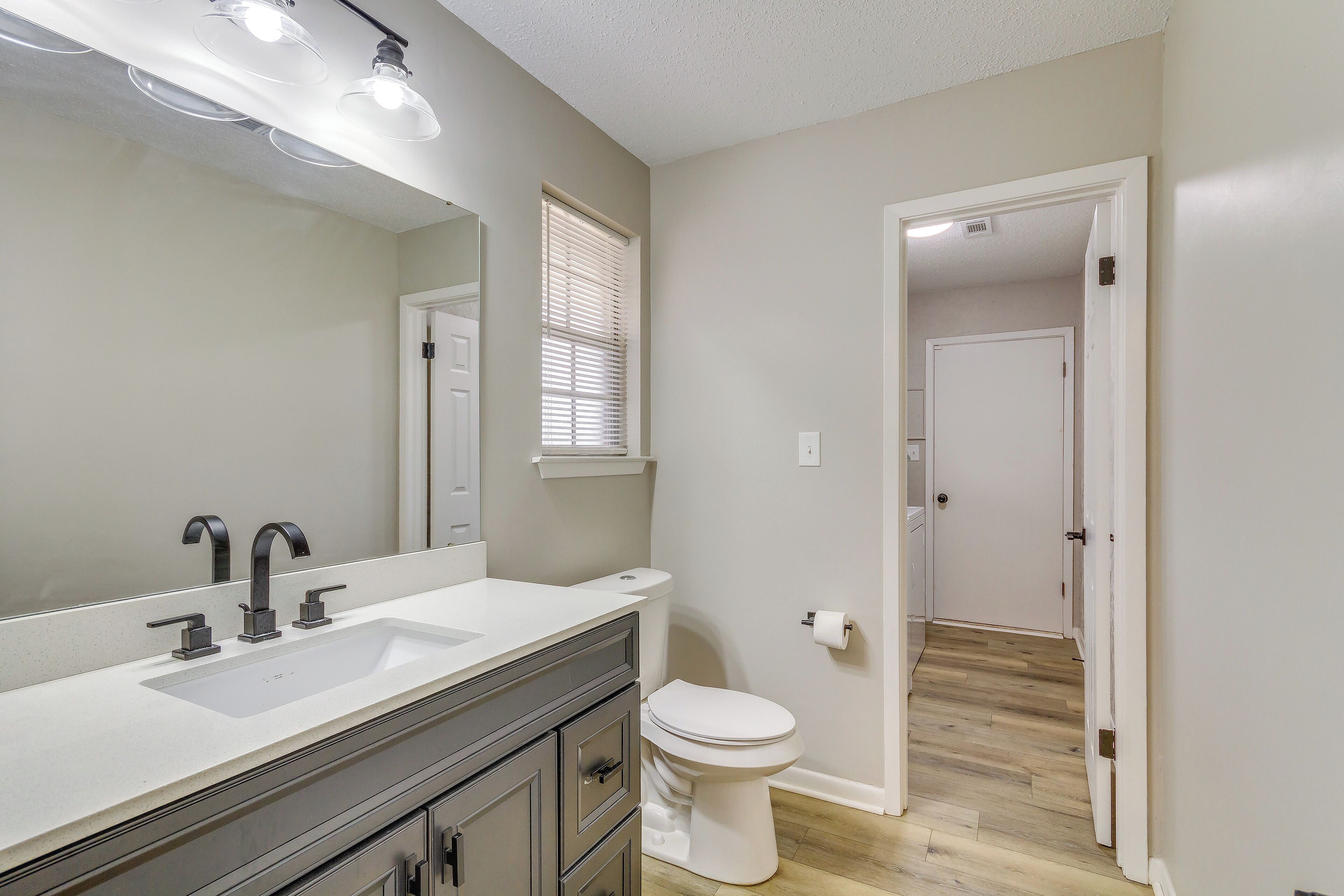 A bathroom with a white sink, a mirror, and a toilet.