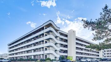 A multi-story parking garage with several levels of parking, surrounded by greenery and a clear sky.