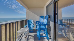 Un balcone con poltroncine Adirondack blu, un tavolino e vista sull'oceano.