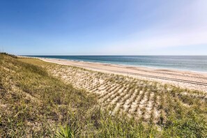 Een strand met een heldere lucht en een zandpad dat naar het water leidt.
