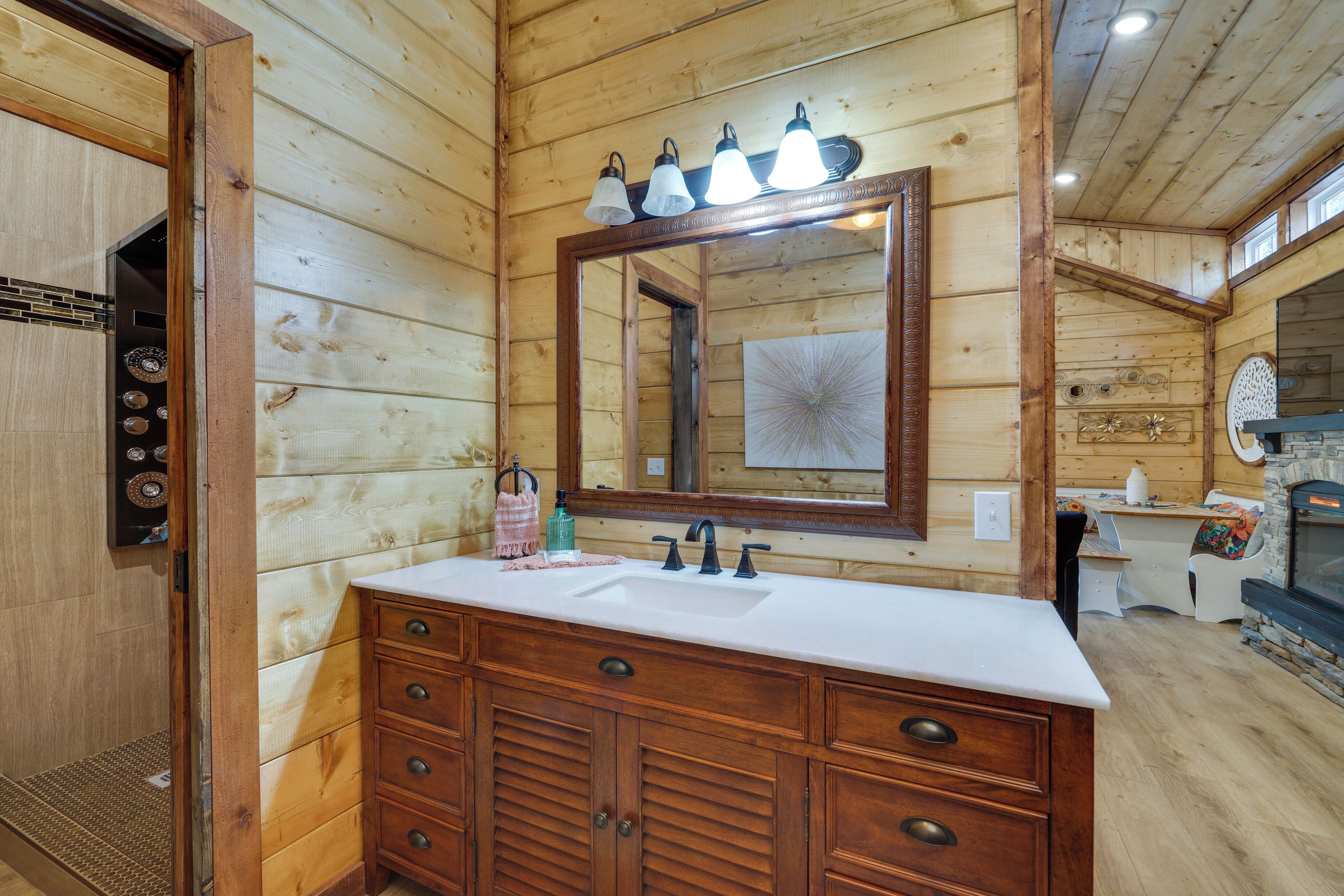 Une salle de bain rustique, avec des murs en bois, un grand miroir, des meubles en bois, un lavabo et un espace douche.