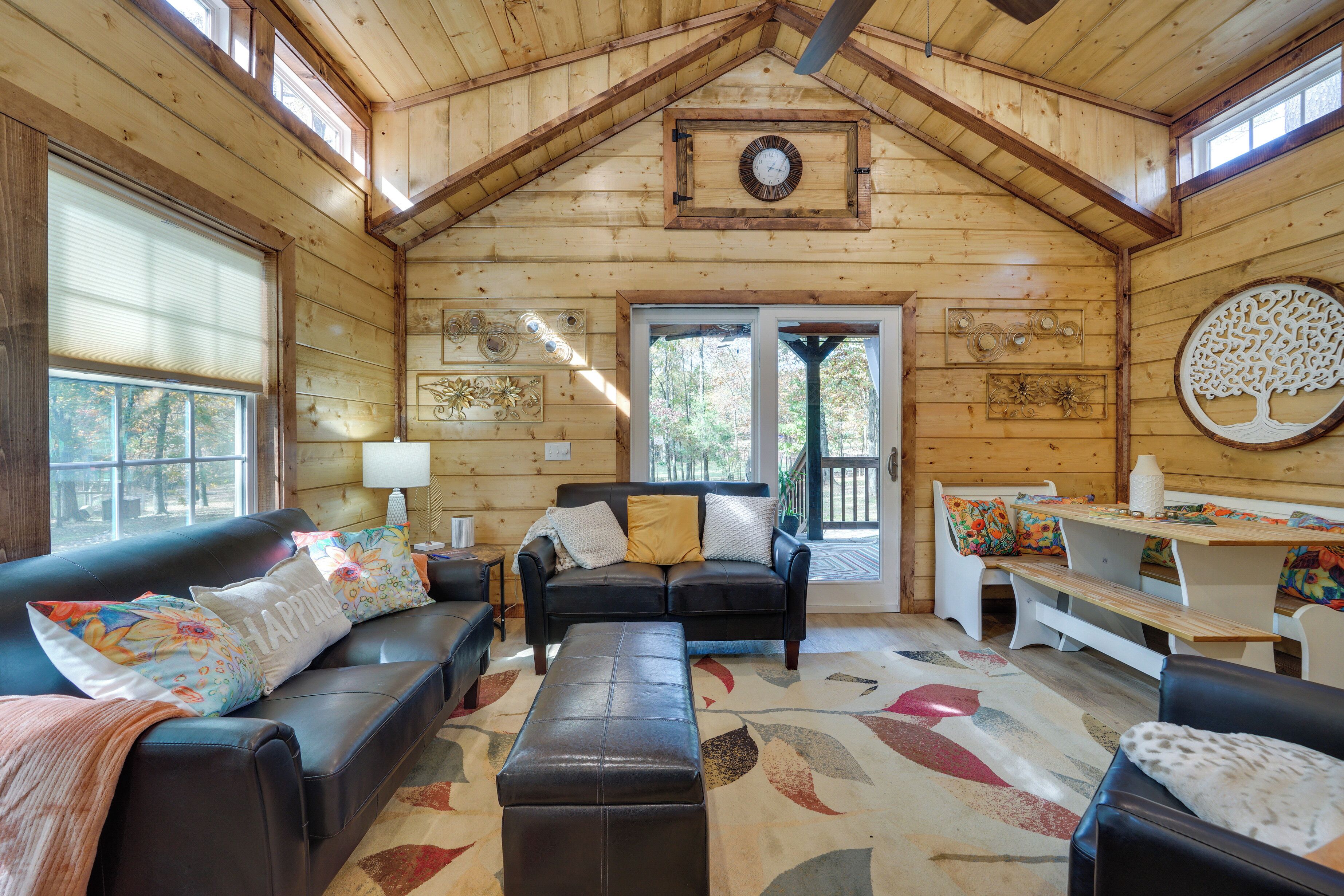 A cozy cabin interior with a wooden interior, a black leather sofa, a bench, and a dining table.