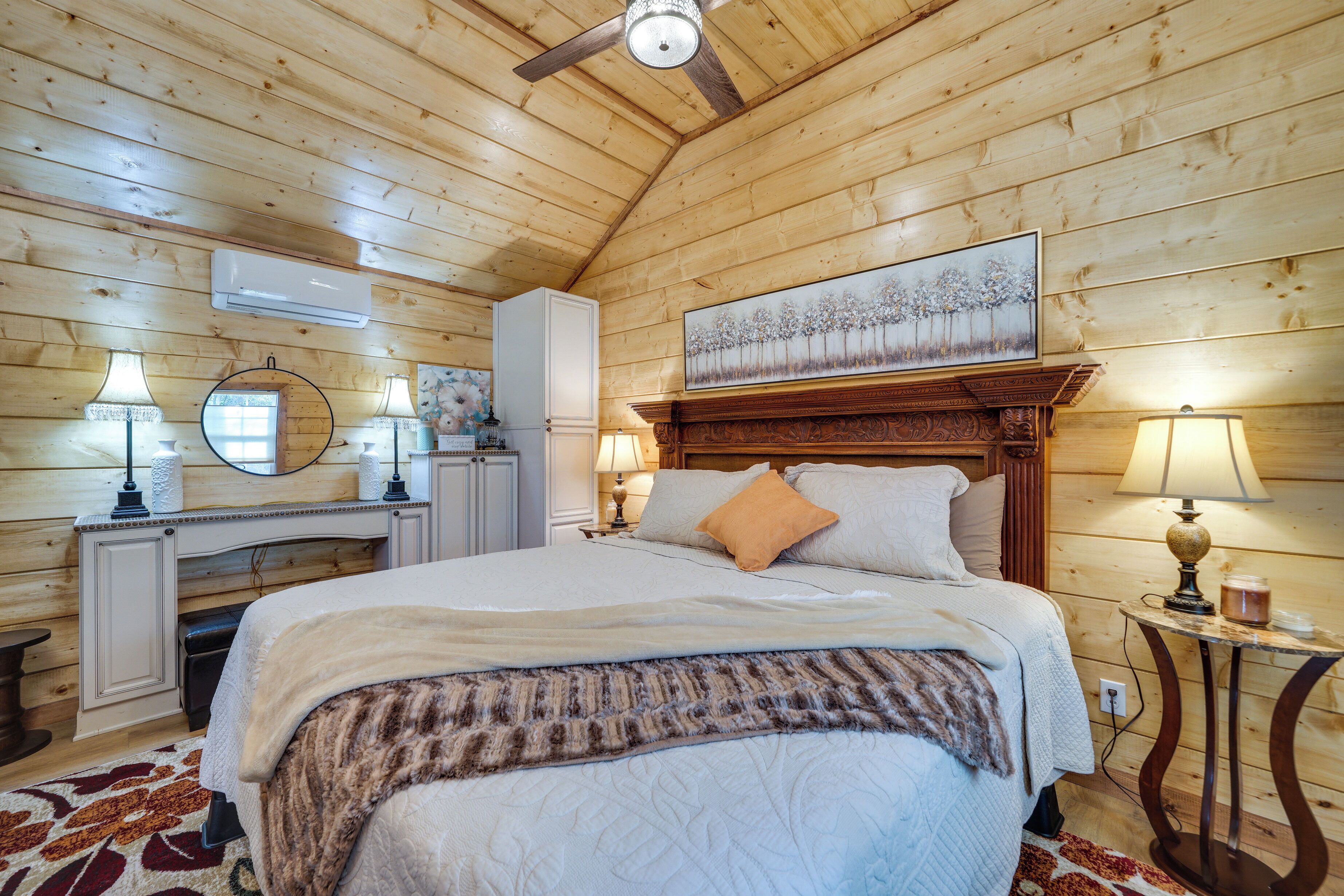 A wooden-paneled bedroom with a bed, bedside lamps, a mirror, and a painting on the wall.