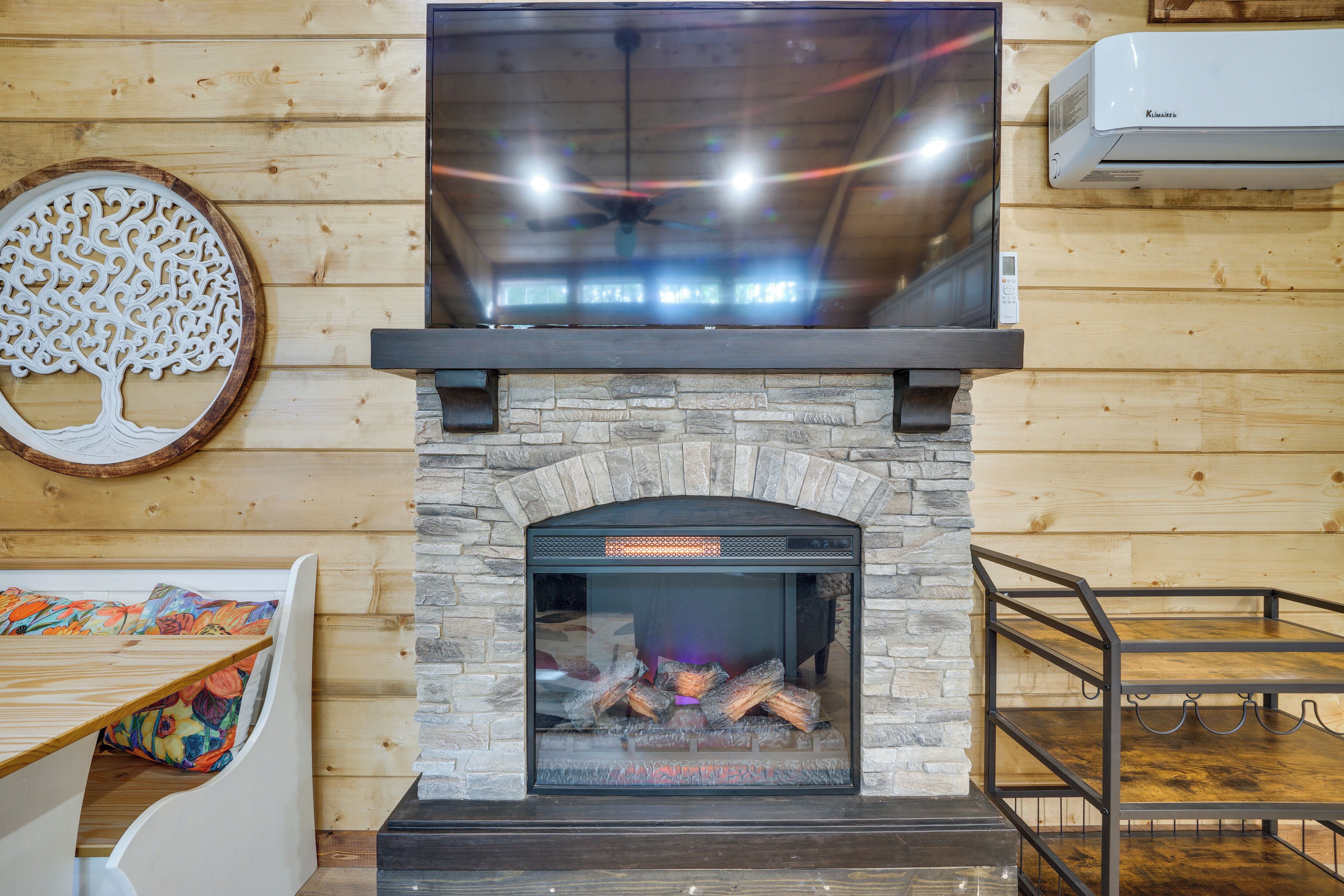 A fireplace with a stone surround, a television mounted above it, and a decorative wall piece.