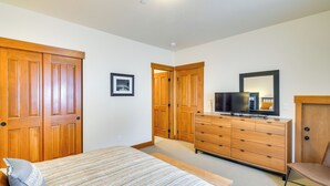 Une chambre à coucher avec un lit, une commode, un téléviseur et des portes en bois.
