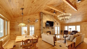 A log cabin interior with a stone fireplace, wooden furniture, and a television. - W Branch Del Cabin Fully Equipped: Private Island (Deposit)
