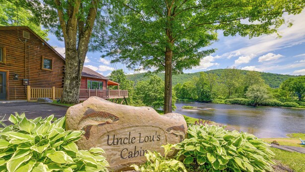 A cabin named Uncle Lou's Cabin surrounded by lush greenery and a river. - W Branch Del Cabin Fully Equipped: Private Island (Deposit)