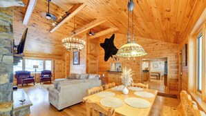 A cozy log cabin interior with a dining area, sofas, and a stone fireplace. - W Branch Del Cabin Fully Equipped: Private Island (Deposit)