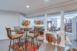 A spacious kitchen with a central island, a dining area with chairs, and a living room with a fireplace.