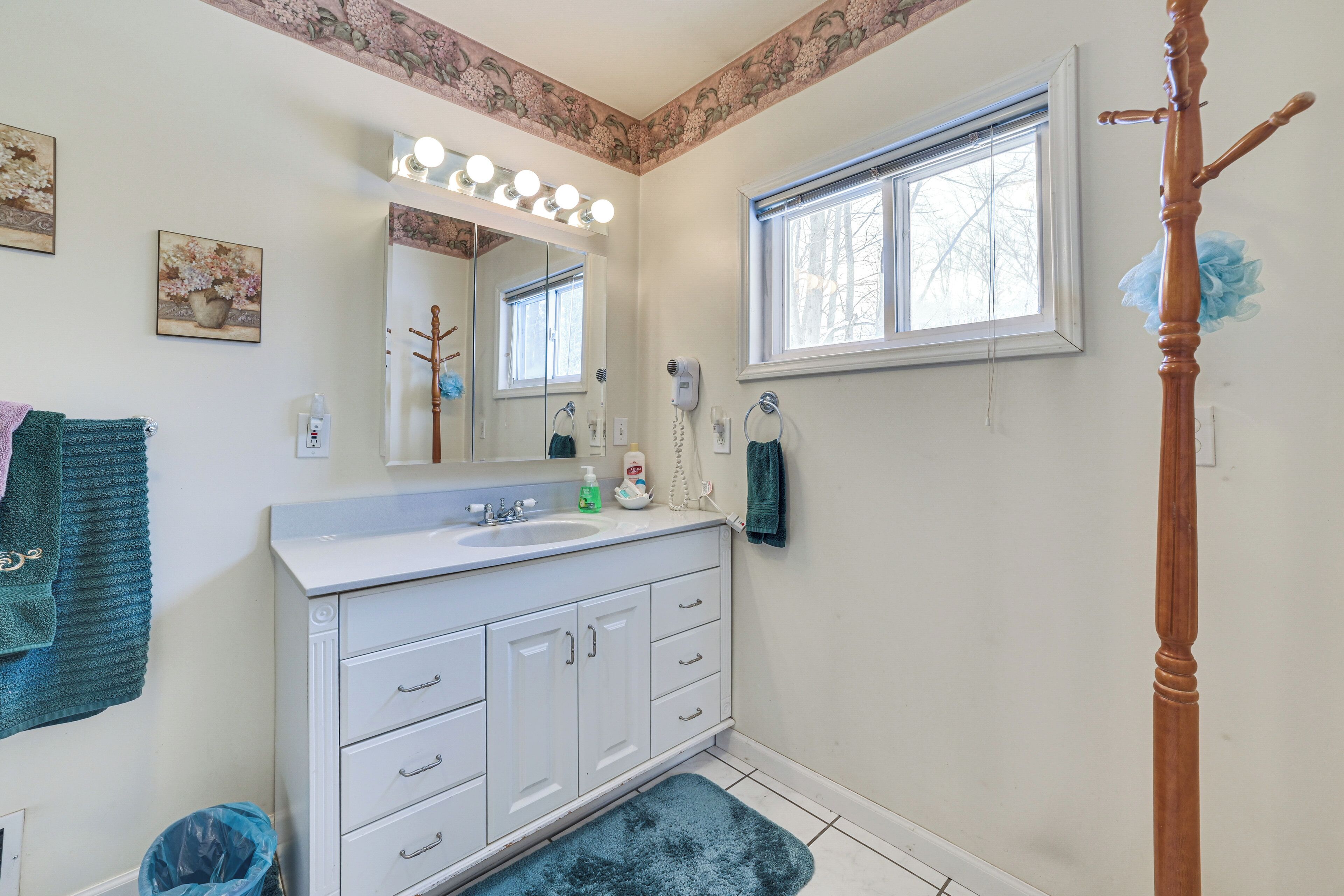 A bathroom with a vanity, mirror, and a window.