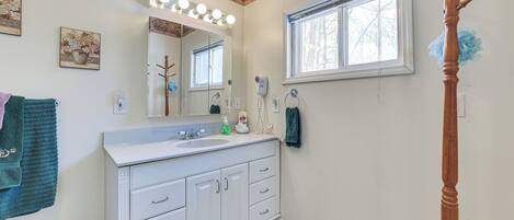 A bathroom with a vanity, mirror, and a window.