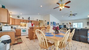 A spacious kitchen with wooden cabinets, a dining area with a wooden table and chairs, and a living area with a sofa and a ceiling fan. - Secluded Mancelona Home w/ Gas Grill! (Mancelona)