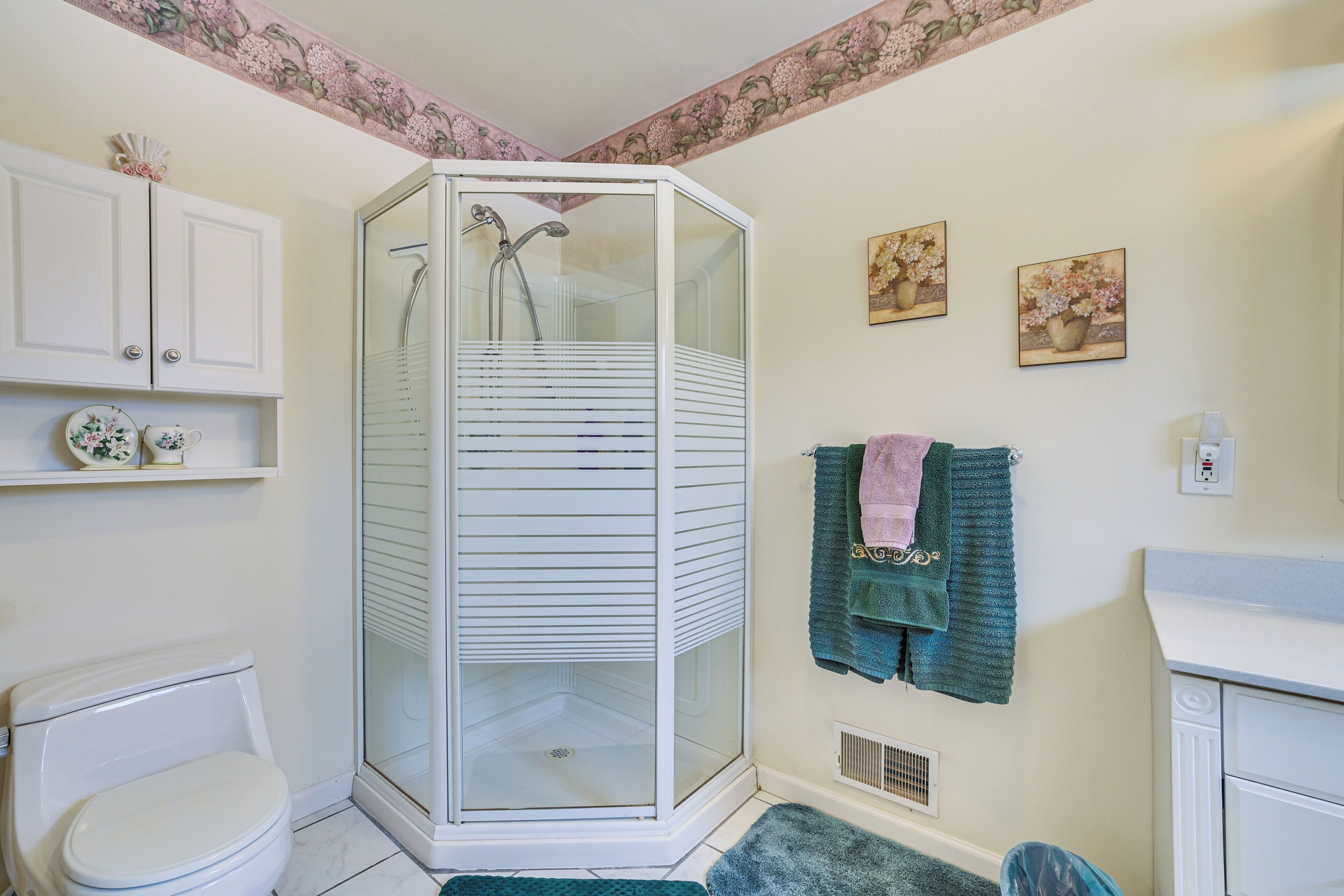 A bathroom with a glass-enclosed shower, a toilet, a sink, and decorative towels.