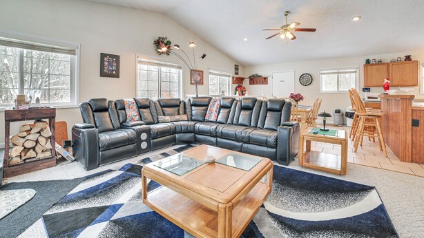 A spacious living room with a sectional sofa, a glass coffee table, and a ceiling fan. - Secluded Mancelona Home w/ Gas Grill! (Mancelona)