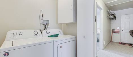 A laundry room with two front-loading washing machines, a water heater, and a drying rack.