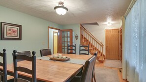 A dining area with a wooden table and chairs, a staircase, and a door leading to another room. - Large Home w/ Deck & Grill ~ 9 Mi to Virginia Tech (Christiansburg)