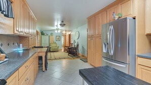A kitchen with wooden cabinets, a stainless steel refrigerator, and a dining area with a table and chairs. - Large Home w/ Deck & Grill ~ 9 Mi to Virginia Tech (Christiansburg)