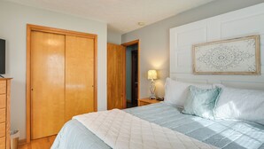 A bedroom with a bed, wooden wardrobe, bedside table with lamp, and a decorative wall piece. - Large Home w/ Deck & Grill ~ 9 Mi to Virginia Tech (Christiansburg)