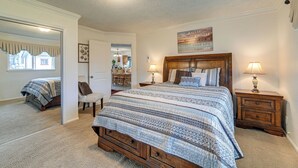 A bedroom with a large bed, two bedside tables with lamps, a mirror, and a door leading to another room. - Family-friendly Winston Vacation Rental w/ Deck! (Winston)